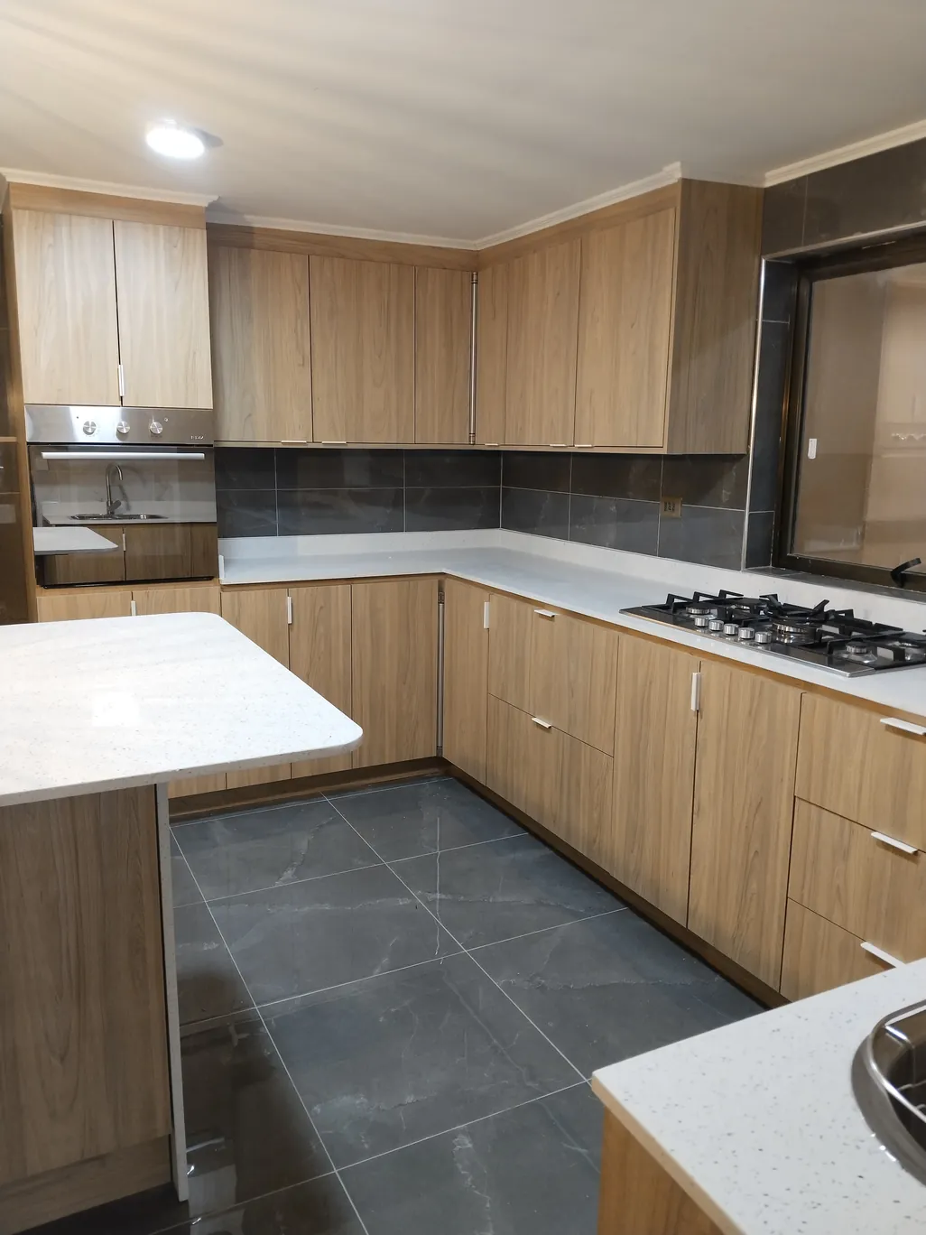 Cocina a medida en L con encimera y muebles de madera clara