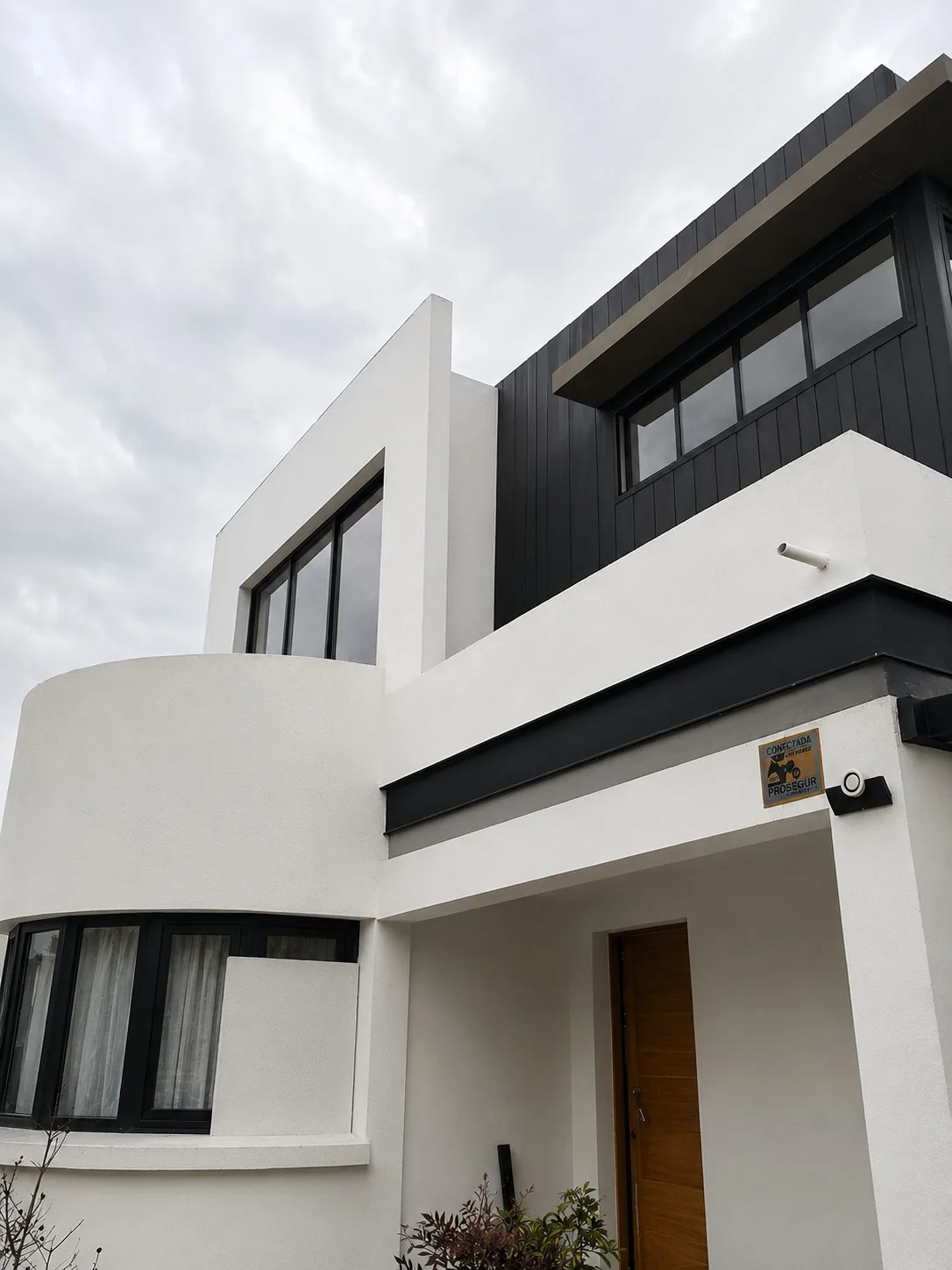 Fachada de vivienda de dos pisos terminada, revestimiento blanco y negro