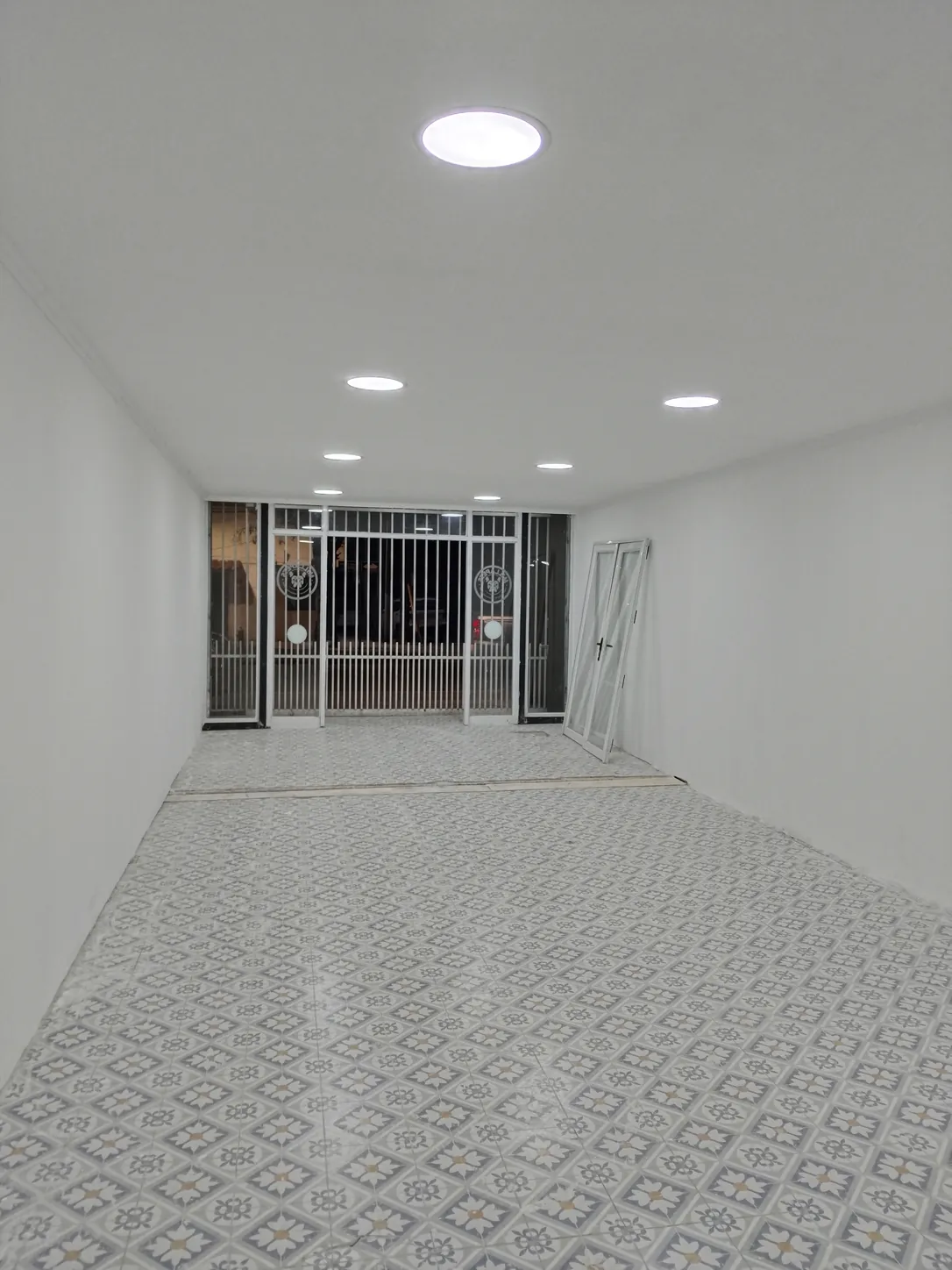 Interior terminado: revestimiento de piso, luminarias y reja al fondo