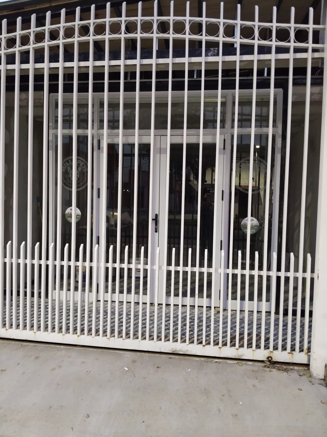 Fachada: reja blanca en arco y acceso vidriado