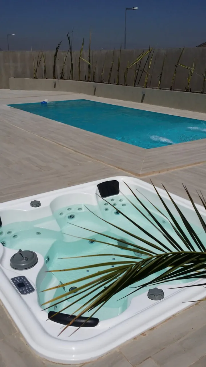 Jacuzzi empotrado en el porcelanato, con la piscina detrás