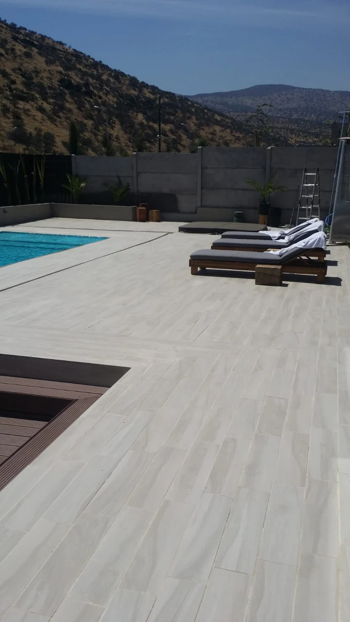 Terraza de porcelanato con reposeras y los cerros de fondo