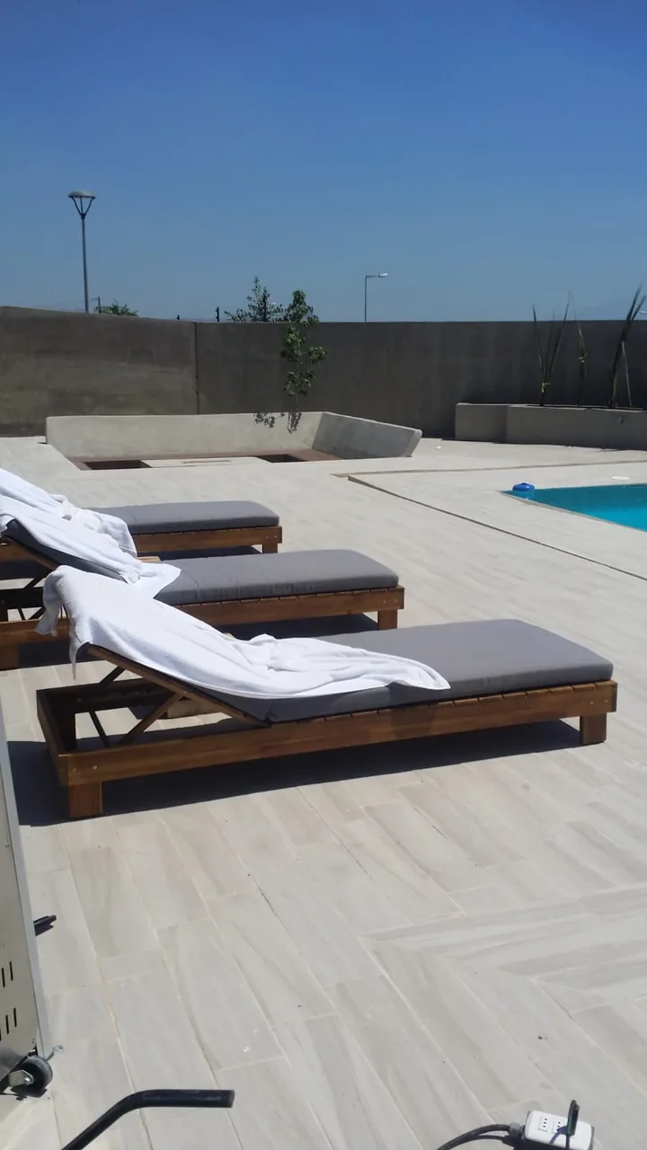 Reposeras sobre la terraza, al borde de la piscina